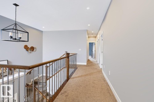 Open upper hallway with recessed lighting and a staircase featuring a wood handrail and metal balusters - 527 Merlin Landing Nw, Edmonton, AB - Indoor Photo Showing Other Room