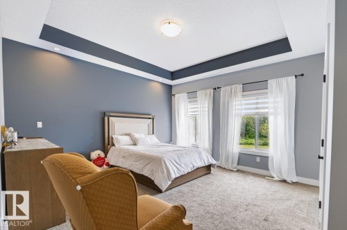 Primary Bedroom Suite with Tray Ceiling and Architectural Detail  Spacious bedroom showcasing a coffered tray ceiling with crown molding, soft recessed lighting, and crisp white trim - 527 Merlin Landing Nw, Edmonton, AB - Indoor Photo Showing Bedroom