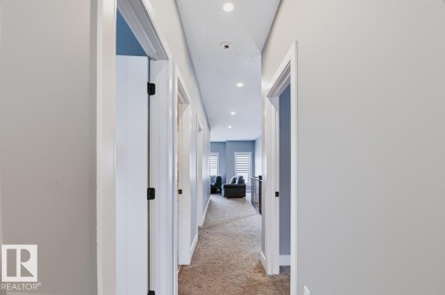 Recessed lighting illuminates the hallway, featuring light-colored carpeting, white trim, and doors with dark hardware - 527 Merlin Landing Nw, Edmonton, AB - Indoor Photo Showing Other Room