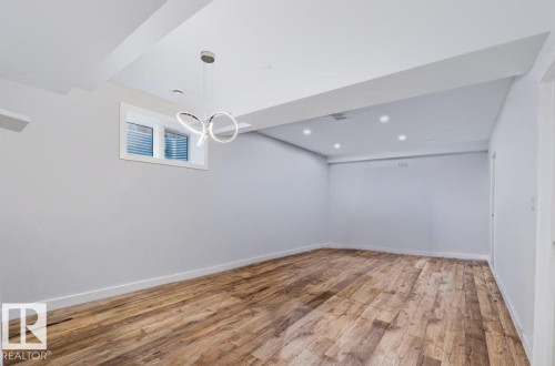 Bright, finished room showcasing newly installed wood-finish flooring, recessed ceiling lighting, and fresh white walls - 527 Merlin Landing Nw, Edmonton, AB - Indoor Photo Showing Other Room