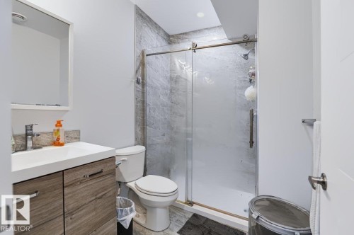Vanity with white countertop, chrome faucet, and wood-finish cabinetry - 527 Merlin Landing Nw, Edmonton, AB - Indoor Photo Showing Bathroom