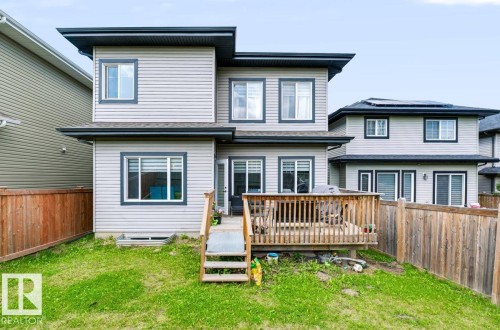 Exterior featuring light gray horizontal siding, dark trim windows, and a multi-level wooden deck with stairs - 527 Merlin Landing Nw, Edmonton, AB - Outdoor With Deck Patio Veranda