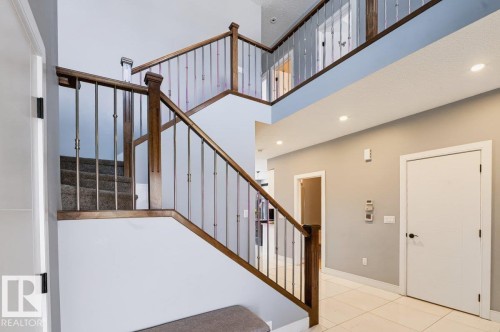 Two-story entry featuring wood-finish railings with metal balusters, tiled flooring, recessed lighting, and white doors with matte black hardware - 527 Merlin Landing Nw, Edmonton, AB - Indoor Photo Showing Other Room