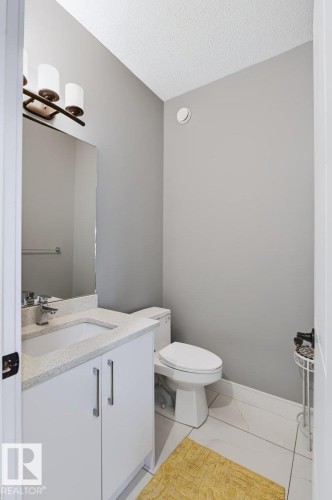 White vanity with a speckled countertop, undermount sink, and chrome faucet - 527 Merlin Landing Nw, Edmonton, AB - Indoor Photo Showing Bathroom