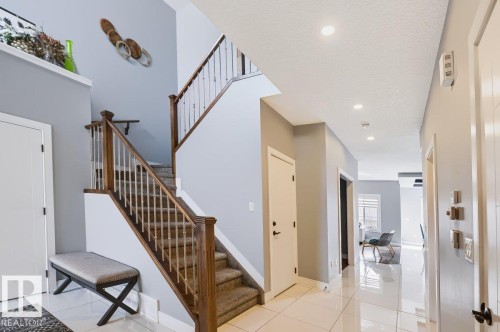 Two-story foyer with a carpeted staircase, wood banister, and metal balusters - 527 Merlin Landing Nw, Edmonton, AB - Indoor Photo Showing Other Room