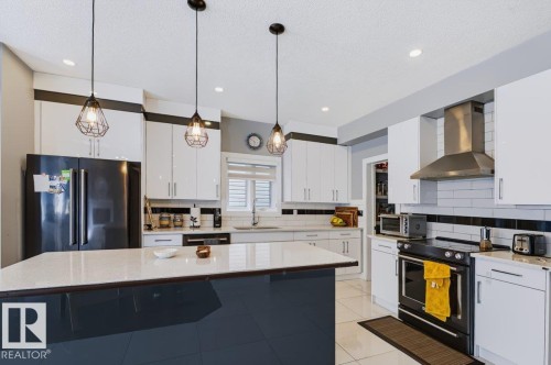 Kitchen featuring white cabinetry, a large island with a light-toned countertop, a black appliance suite, and pendant lighting - 527 Merlin Landing Nw, Edmonton, AB - Indoor Photo Showing Kitchen With Upgraded Kitchen