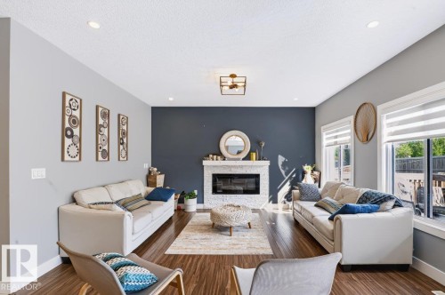 Hardwood-finish flooring, recessed lighting, and a white stone-faced fireplace with a mantel - 527 Merlin Landing Nw, Edmonton, AB - Indoor Photo Showing Living Room With Fireplace