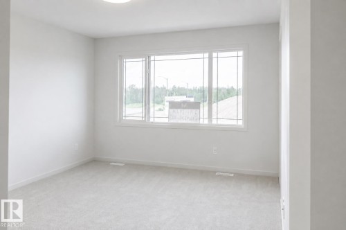 Neutral wall tones complemented by light-toned carpeting and a fixed overhead lighting fixture - 219 157 Avenue Ne, Edmonton, AB - Indoor Photo Showing Other Room