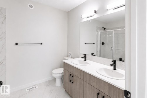Dual vanity with undermount sinks, wood-finish cabinetry, and matte black fixtures - 219 157 Avenue Ne, Edmonton, AB - Indoor Photo Showing Bathroom