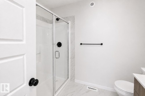 Glass-enclosed shower with matte black fixtures, white tiled walls, and a white shower pan - 219 157 Avenue Ne, Edmonton, AB - Indoor Photo Showing Bathroom