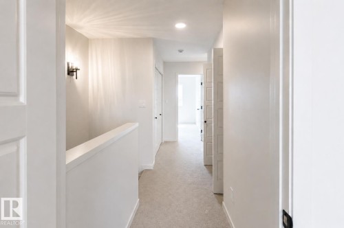 Hallway with neutral carpeting, recessed lighting, and a modern wall sconce - 219 157 Avenue Ne, Edmonton, AB - Indoor Photo Showing Other Room
