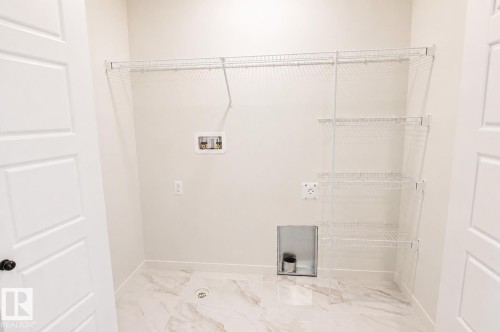 White wire shelving, white paneled door, light-toned walls, and marble-look floor tiling - 219 157 Avenue Ne, Edmonton, AB - Indoor With Storage