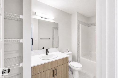 Full bathroom featuring a single vanity with wood-finish cabinetry, a rectangular undermount sink, and a white countertop - 219 157 Avenue Ne, Edmonton, AB - Indoor Photo Showing Bathroom