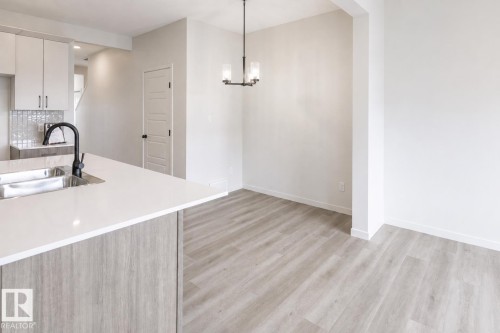 Kitchen island with white countertop and integrated stainless steel sink - 219 157 Avenue Ne, Edmonton, AB - Indoor Photo Showing Kitchen With Double Sink