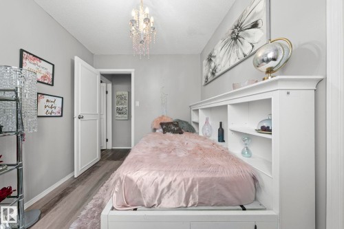 Light gray walls, wood-finish flooring, and a crystal chandelier - 11119 31St Nw Nw, Edmonton, AB - Indoor Photo Showing Bedroom