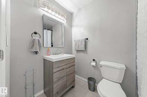 Modern vanity with wood-finish cabinetry, integrated sink, and chrome fixtures - 11119 31St Nw Nw, Edmonton, AB - Indoor Photo Showing Bathroom