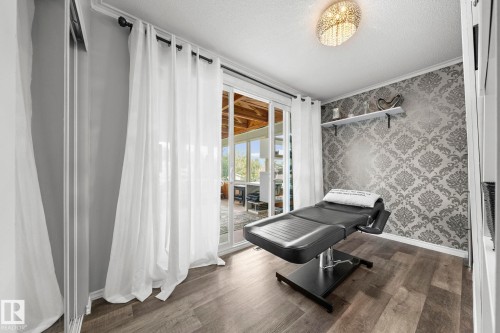 Sliding glass door, wood-finish flooring, accent wall with patterned wallpaper, built-in shelving, and a decorative ceiling light fixture - 11119 31St Nw Nw, Edmonton, AB - Indoor Photo Showing Other Room