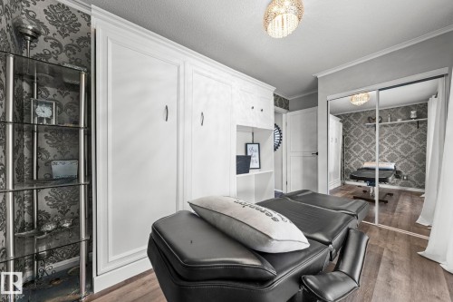 Built-in cabinetry with integrated shelving, mirrored closet doors, wood-finish flooring, and a crystal-style flush mount light fixture - 11119 31St Nw Nw, Edmonton, AB - Indoor