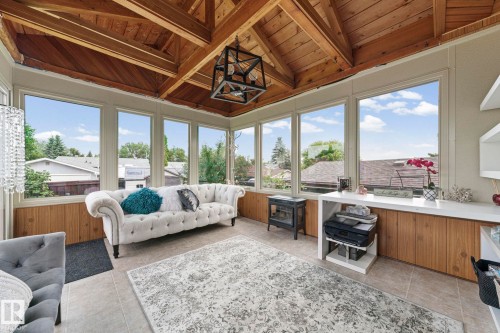 Vaulted wood-finish ceiling with exposed beams, multiple large windows, wood-finish paneling, and ceramic tile flooring - 11119 31St Nw Nw, Edmonton, AB - Indoor Photo Showing Living Room