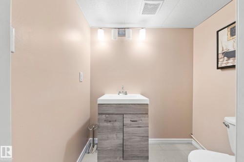 Wood-finish vanity with white countertop and integrated sink - 11119 31St Nw Nw, Edmonton, AB - Indoor Photo Showing Bathroom