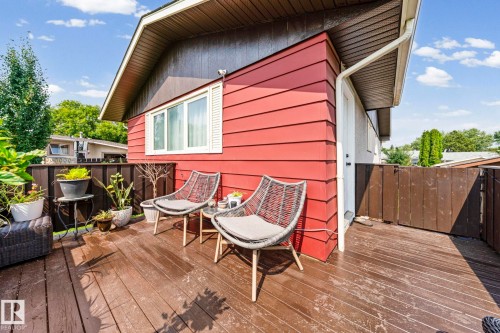 Expansive wood-finish deck with privacy fencing, featuring a white window and a white door with a black handle - 11119 31St Nw Nw, Edmonton, AB - Outdoor With Deck Patio Veranda With Exterior