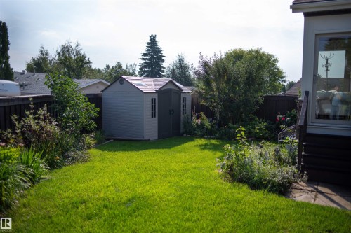 Expansive backyard featuring a manicured lawn, established garden beds, a utility shed, and privacy fencing - 11119 31St Nw Nw, Edmonton, AB - Outdoor