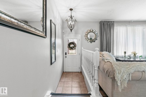 Foyer with tile flooring, decorative entry door with privacy glass, and a traditional chandelier - 11119 31St Nw Nw, Edmonton, AB - Indoor