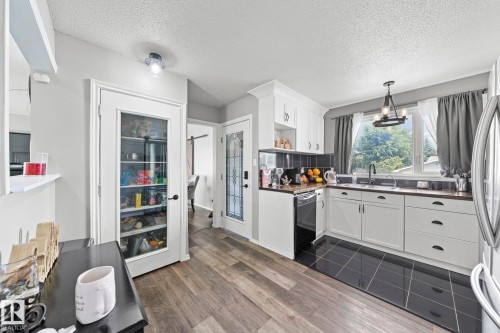 White cabinetry with dark hardware, dark countertops, and a black tile backsplash - 11119 31St Nw Nw, Edmonton, AB - Indoor Photo Showing Kitchen With Double Sink