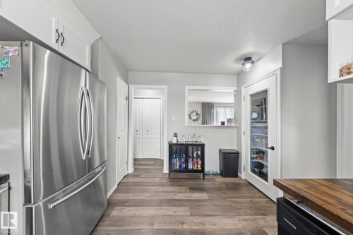 Stainless steel refrigerator, wood-finish flooring, white paneled doors, built-in shelving, and transom window - 11119 31St Nw Nw, Edmonton, AB - Indoor