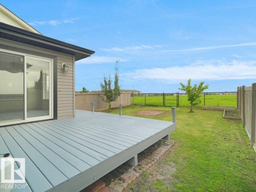 Spacious backyard featuring a built-in wood deck, sliding glass door access, and a manicured lawn - 3010 17A Ave Nw, Edmonton, AB - Outdoor
