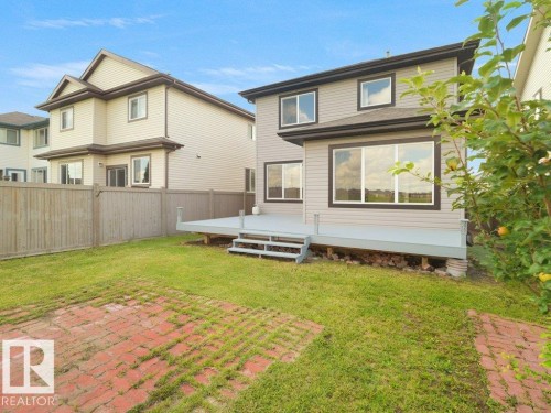 Expansive backyard featuring a wood privacy fence, a gray painted deck with steps, and a red brick patio area - 3010 17A Ave Nw, Edmonton, AB - Outdoor