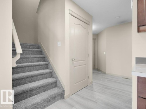 Carpeted staircase with painted handrail, solid interior doors, light wood-finish flooring, and light-toned walls - 3010 17A Ave Nw, Edmonton, AB - Indoor Photo Showing Other Room