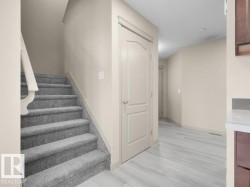 Carpeted staircase with painted handrail, solid interior doors, light wood-finish flooring, and light-toned walls - 