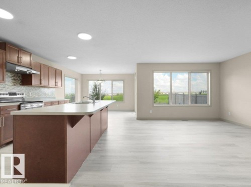Open-concept kitchen and living area featuring a large center island with integrated sink, stainless steel appliances, and a tiled backsplash - 3010 17A Ave Nw, Edmonton, AB - Indoor Photo Showing Kitchen