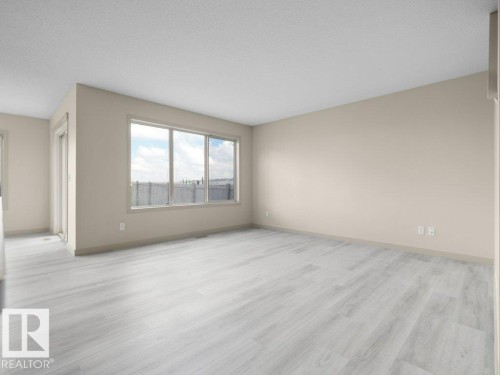 Bright interior with a large window, light-toned walls, and wood-finish flooring - 3010 17A Ave Nw, Edmonton, AB - Indoor Photo Showing Other Room
