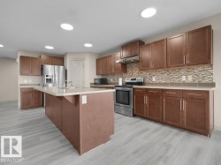 Kitchen featuring wood-finish flooring, recessed lighting, and a center island with a sink - 