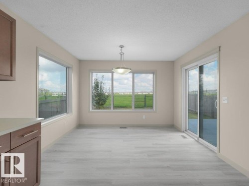 Open-concept dining area featuring light wood-finish flooring, a contemporary pendant light fixture, and multiple windows - 3010 17A Ave Nw, Edmonton, AB -  Photo Showing Other Room