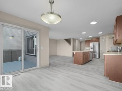Open-concept living space with wood-finish flooring, recessed lighting, and a sliding glass door to an outdoor deck - 