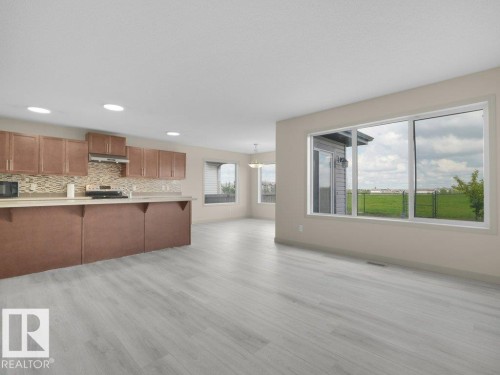 Open-concept layout featuring light wood-finish flooring, recessed lighting, and large windows - 3010 17A Ave Nw, Edmonton, AB - Indoor Photo Showing Kitchen