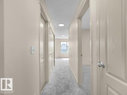 Hallway with recessed lighting, light-toned walls, and grey carpet flooring - 