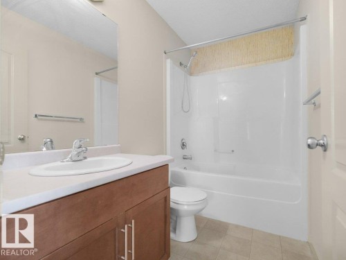 Bathroom featuring a white integrated sink, wood-finish vanity, and a tub/shower combination - 3010 17A Ave Nw, Edmonton, AB - Indoor Photo Showing Bathroom
