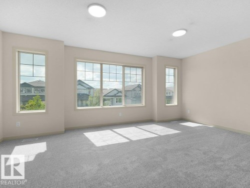 Spacious room featuring multiple windows, neutral wall tones, light gray carpeting, and two ceiling-mounted circular light fixtures - 3010 17A Ave Nw, Edmonton, AB - Indoor Photo Showing Other Room