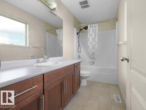 White single vanity with wood-finish cabinetry, integrated sink, and chrome faucet - 3010 17A Ave Nw, Edmonton, AB - Indoor Photo Showing Bathroom