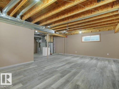 Expansive room featuring wood-finish flooring, neutral-toned walls, and exposed ceiling joists - 3010 17A Ave Nw, Edmonton, AB - Indoor Photo Showing Basement