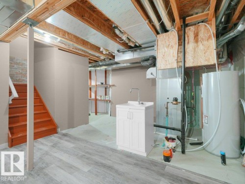Finished wood-finish flooring with a white utility sink cabinet and a chrome faucet - 3010 17A Ave Nw, Edmonton, AB - Indoor Photo Showing Basement