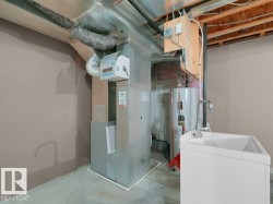 Galvanized sheet metal ductwork, furnace unit, water heater, and utility sink with a chrome faucet - 