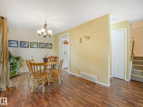 Wood-finish flooring throughout the main area, featuring a decorative ceiling light fixture - 18417 66 Avenue Nw, Edmonton, AB - Indoor Photo Showing Dining Room