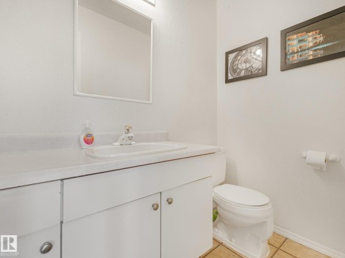 White vanity with integrated sink, chrome faucet, and white framed mirror - 18417 66 Avenue Nw, Edmonton, AB - Indoor Photo Showing Bathroom