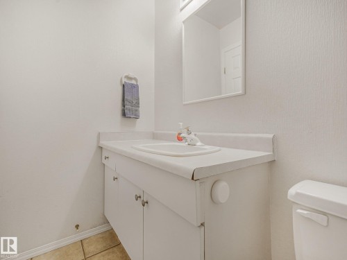 White vanity with an integrated sink and base cabinetry, complemented by a wall-mounted mirror - 18417 66 Avenue Nw, Edmonton, AB - Indoor Photo Showing Bathroom