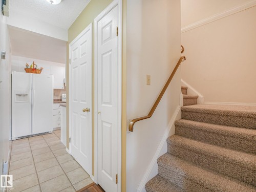 Tiled flooring, white paneled doors, carpeted stairs, and a wooden handrail - 18417 66 Avenue Nw, Edmonton, AB - Indoor Photo Showing Other Room